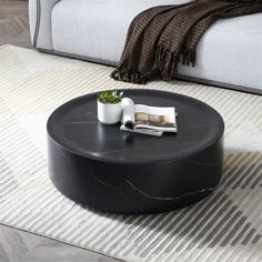 a black coffee table sitting on top of a rug in front of a white couch