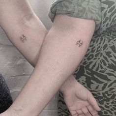 two people holding hands with small tattoos on them