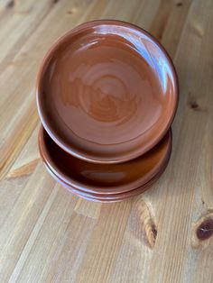 two brown plates sitting on top of a wooden table