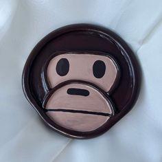 a monkey face painted on the side of a brown and white wall mounted plaque with black eyes