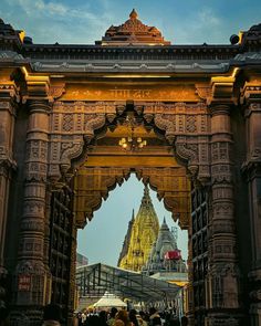 people are walking under an ornate archway in the evening time, with lights on them