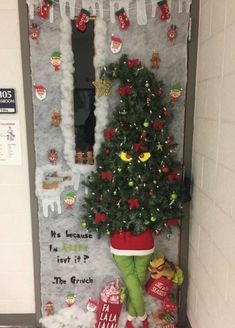 a decorated door with a christmas tree and stockings on it, in front of an elf's feet