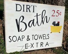 a sign that is on the side of a tree in front of dirt bath soap and towels extra