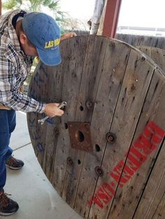 a man in plaid shirt and blue hat working on a wooden fence with screwdrivers