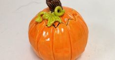 a ceramic pumpkin with an owl sitting on it