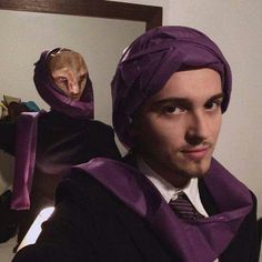 a man wearing a purple turban and looking at himself in the mirror