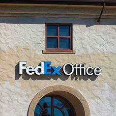 the fed ex office sign is on the side of a building with an arched window