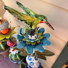 three ceramic birds sitting on top of each other in vases with flowers around them