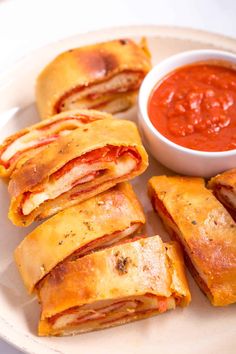 several pastries on a plate with a bowl of tomato sauce