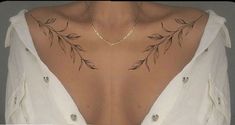 the back of a woman's neck with leaves on it and a chain around her neck