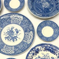 several blue and white plates with flowers on them are lined up against a white wall