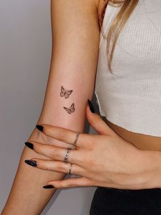 two women with tattoos on their arms holding each other's hands and one has a butterfly tattoo on her left arm