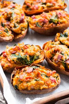 baked stuffed sweet potatoes with spinach and ham in them on a baking sheet, ready to be eaten