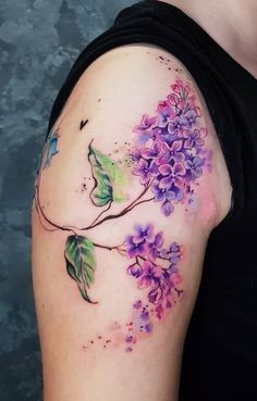 a woman's arm with purple flowers and green leaves on the left side of her body