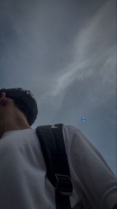 a man is looking up at the sky with an object in the distance behind him