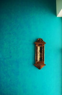 a blue wall with a wooden clock on it