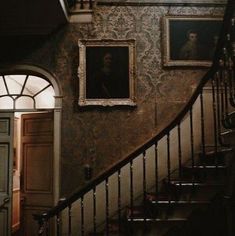 a staircase with pictures on the wall and paintings on the wall above it in an old house