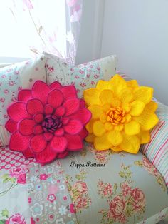 two crocheted flower pillows sitting on top of a floral couch cushiones and pillow covers