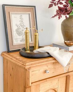 a wooden dresser topped with a potted plant and two golden faucets on top of it