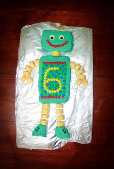 a cake made to look like a robot on top of tin foil with green and yellow decorations