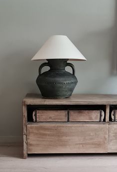 a lamp sitting on top of a wooden table next to a dresser with drawers underneath it