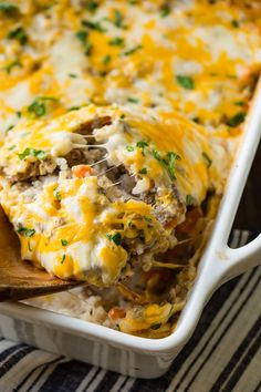 a casserole dish with meat and cheese on top is being scooped from the casserole