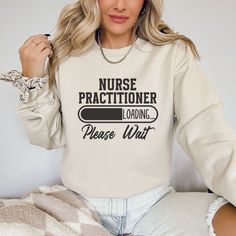 Stay warm and stylish with this Nurse Practitioner sweatshirt featuring the clever text "Nurse Practitioner Loading, Please Wait." This cozy and comfortable sweatshirt is a great gift for a college student studying to become a nurse practitioner or a thoughtful gift for any hardworking healthcare professional in your life. Show off your dedication to the nursing field while staying cozy and fashionable with this unique sweatshirt. Perfect for everyday wear or for those relaxing nights at home, t Nursing Long Sleeve Relaxed Fit Sweatshirt, Long Sleeve Nursing Sweatshirt With Relaxed Fit, Relaxed Fit Long Sleeve Nursing Top, Loading Please Wait, Nurse Week, Nurses Week Gifts, Becoming A Nurse, Unique Sweatshirt, New Nurse