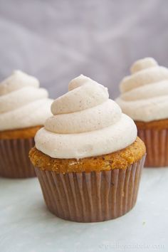 three cupcakes with white frosting on top