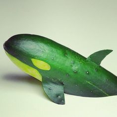 a green toy whale with yellow spots on it's body and tail, sitting on a white surface