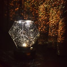 a light that is on top of a table in front of some trees and lights