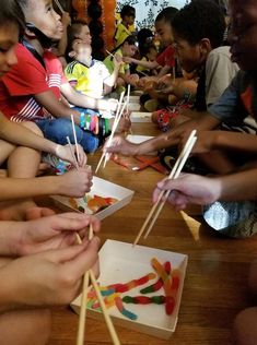 children are sitting on the floor and playing with toothpicks in front of them