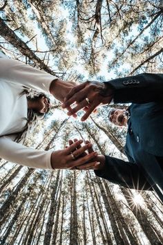 two people holding hands in the middle of a forest