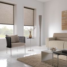 a living room filled with furniture and windows covered in roman blind shades on top of them