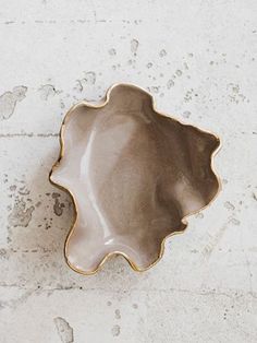 a white and gold dish sitting on top of a counter next to a brick wall