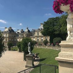 a statue in front of a large building with lots of flowers on the top of it