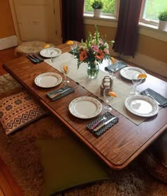 a wooden table with plates and place settings on it