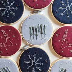 embroidered christmas ornaments are arranged in rows on a white surface with snowflakes and trees