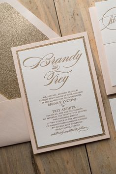 the wedding stationery is laid out on a wooden table with gold glitter and white paper