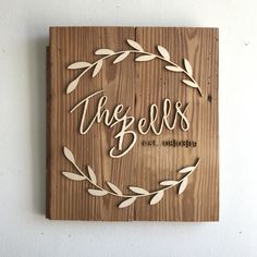 a wooden plaque that says the bells are blooming with leaves around it on a white wall