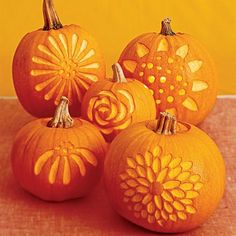 four carved pumpkins sitting on top of a table next to each other with flowers painted on them