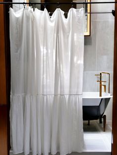 a white shower curtain in a bathroom next to a bath tub