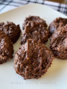 four chocolate cookies on a white plate