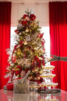 a christmas tree decorated with red, gold and silver ornaments in front of a window