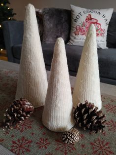 three white knitted cones sitting on top of a table next to two pine cones