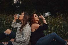 two women are sitting on the ground drinking from their bottles and looking up into the sky