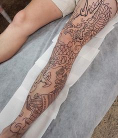 a person laying down with a tattoo on their arm and leg next to a cell phone