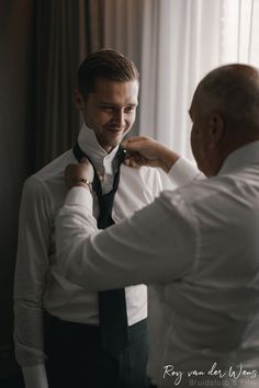 a man helping another man put on his tie