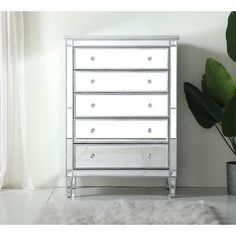 a white chest of drawers sitting next to a potted plant