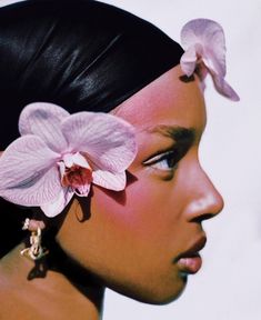 a close up of a person with a flower in her hair and an earring