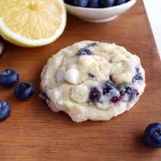 a cookie with blueberries and lemons on a cutting board next to some fruit